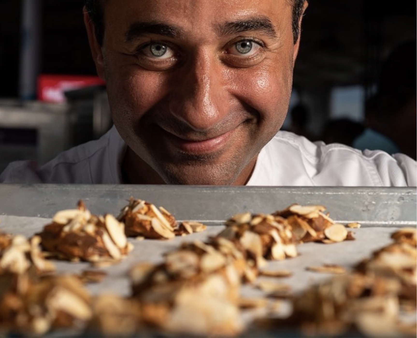 Carlo Raciti posing in front of fresh baked almotti goods