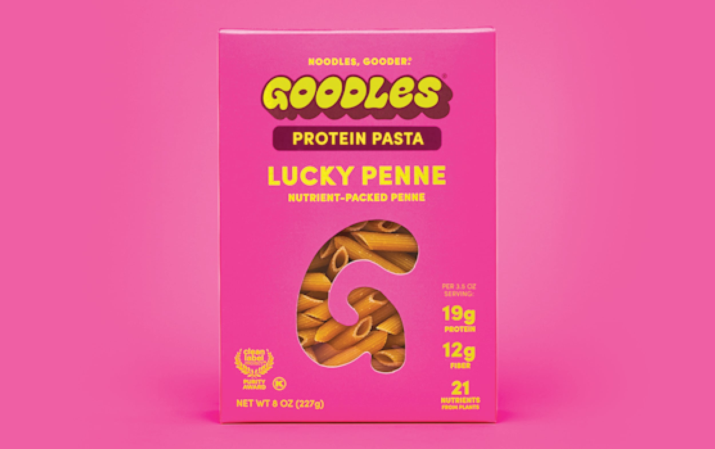 A pink box of Goodles Protein Pasta, labeled Lucky Penne. The packaging highlights 19g protein, 12g fiber, and 21 nutrients per serving, with a pasta-shaped window in the center.