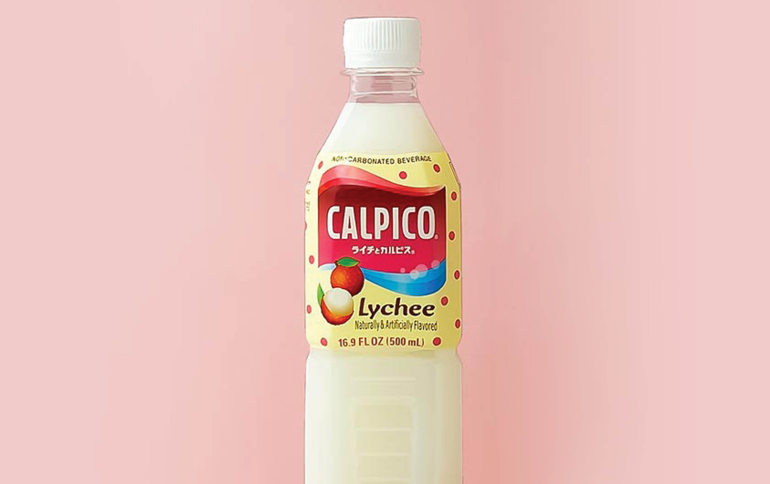 A bottle of Calpico lychee-flavored soft drink with a white cap, white liquid inside, and a colorful label featuring lychee fruit, set against a light pink background.