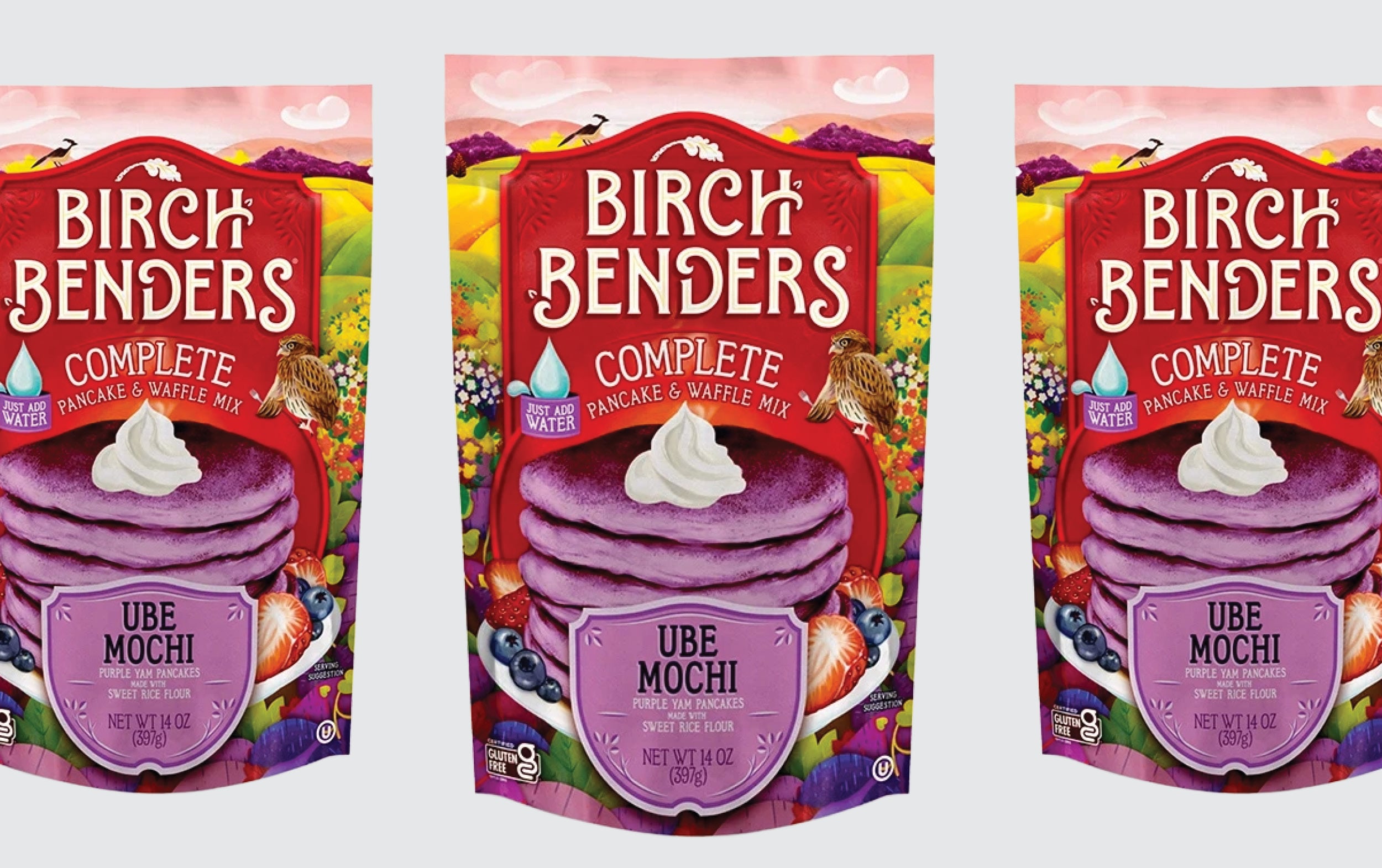 Three packages of Birch Benders Complete Ube Mochi Pancake & Waffle Mix with images of purple pancakes, whipped cream, and fruit on a colorful, scenic background.